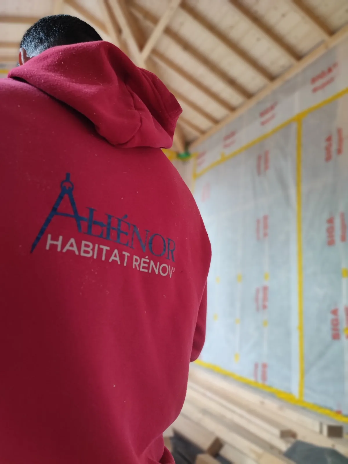 Un charpentier Aliénor Habitat Rénov' posant un pare-vapeur sur un chantier en Gironde