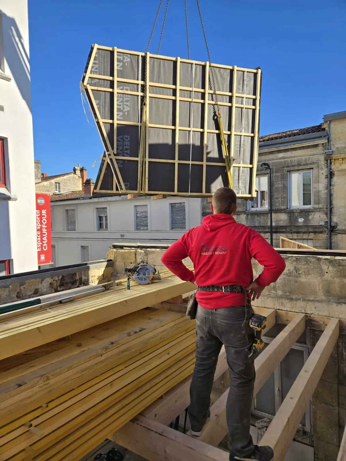 Un charpentier Aliénor Habitat Rénov' guidant le levage d'un caisson à ossature bois